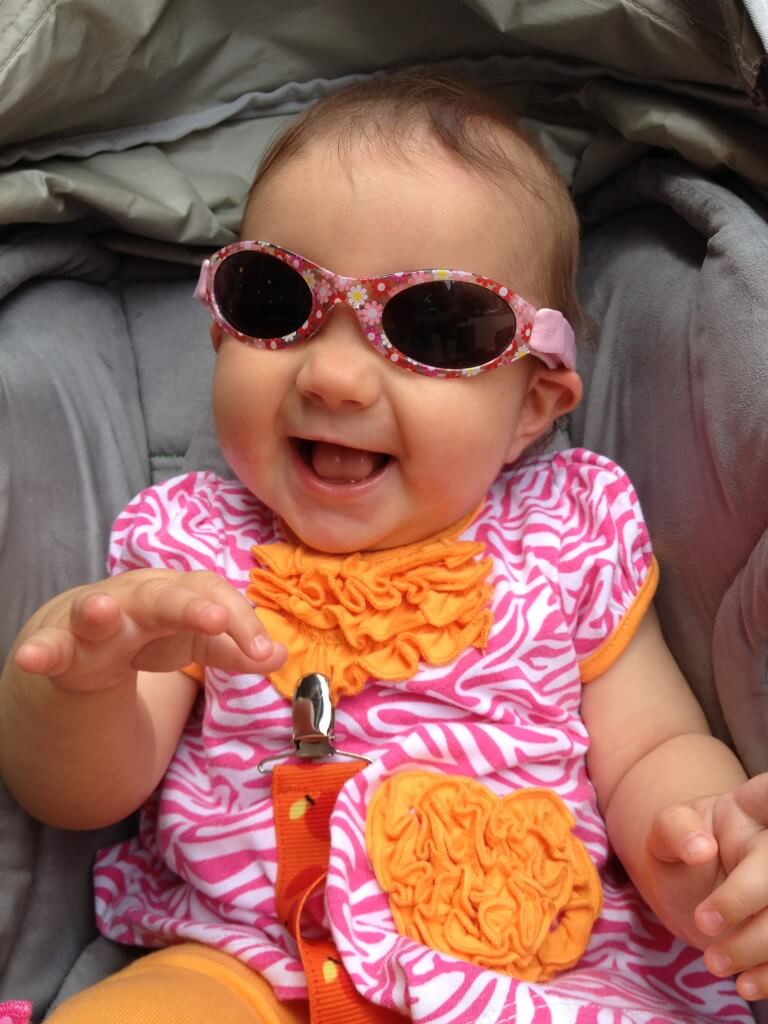 Mikayla smiling in her stroller, wearing floral sunglasses