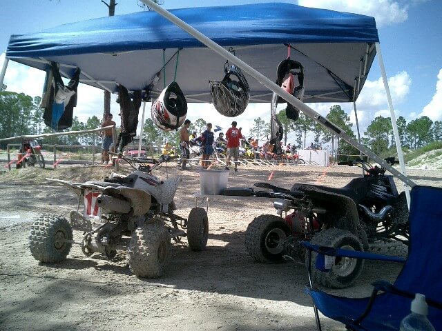 Pit area at a hare scramble — ATVs and gear under a canopy